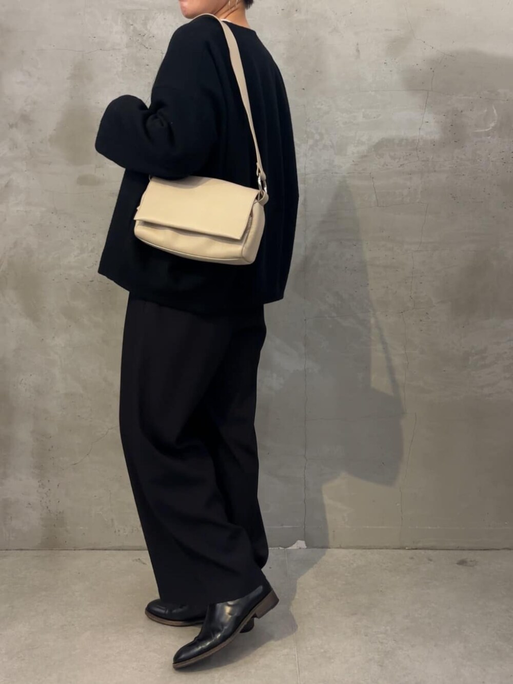 ブラック系のノーカラーコート、ブラック系のその他パンツ、ホワイト系のショルダーバッグを着用したレディースの冬コーディネートの7枚目の写真