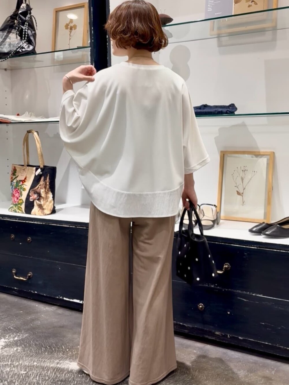 ベージュ系のその他パンツ、ブラック系のトートバッグ、ホワイト系のTシャツ/カットソーを着用したレディースの春コーディネートの4枚目の写真