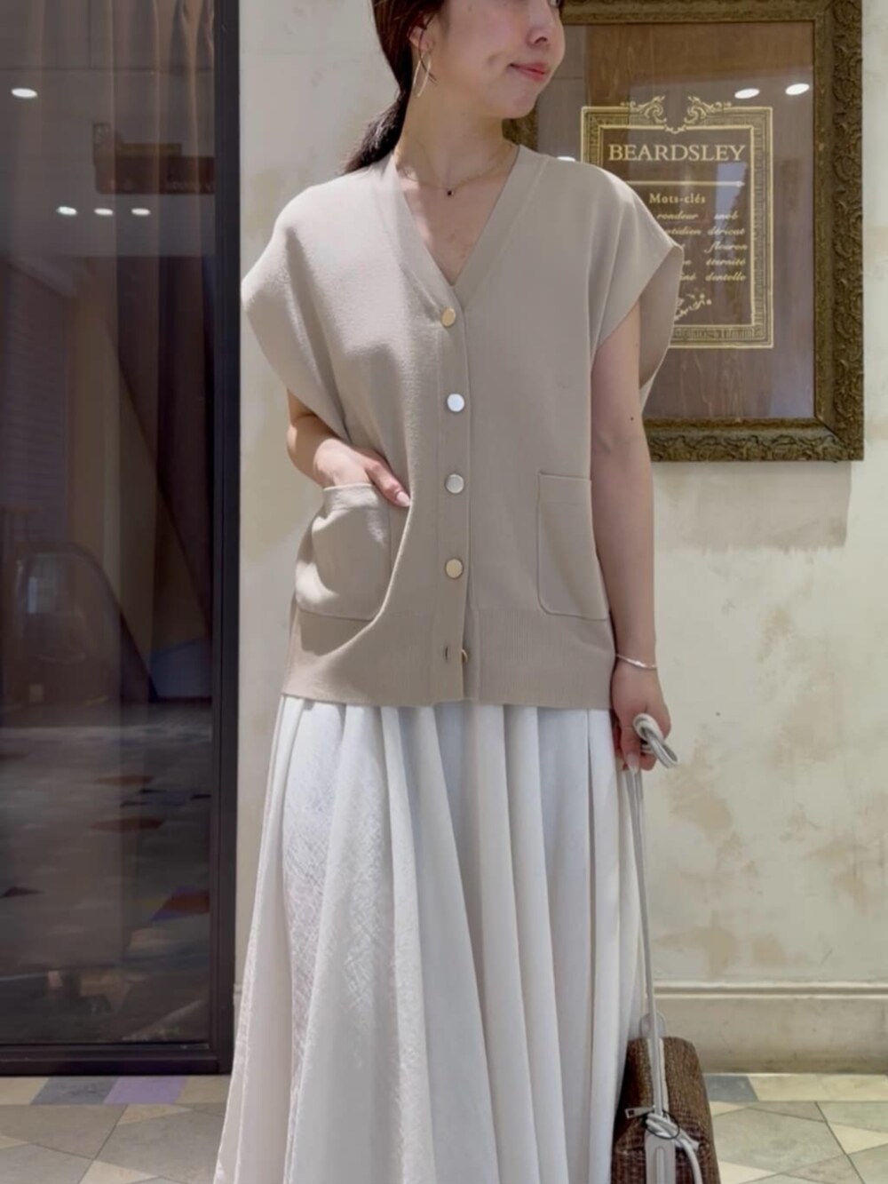 ホワイト系のスカート、ベージュ系のカーディガン/ボレロを着用したレディースの春コーディネートの6枚目の写真