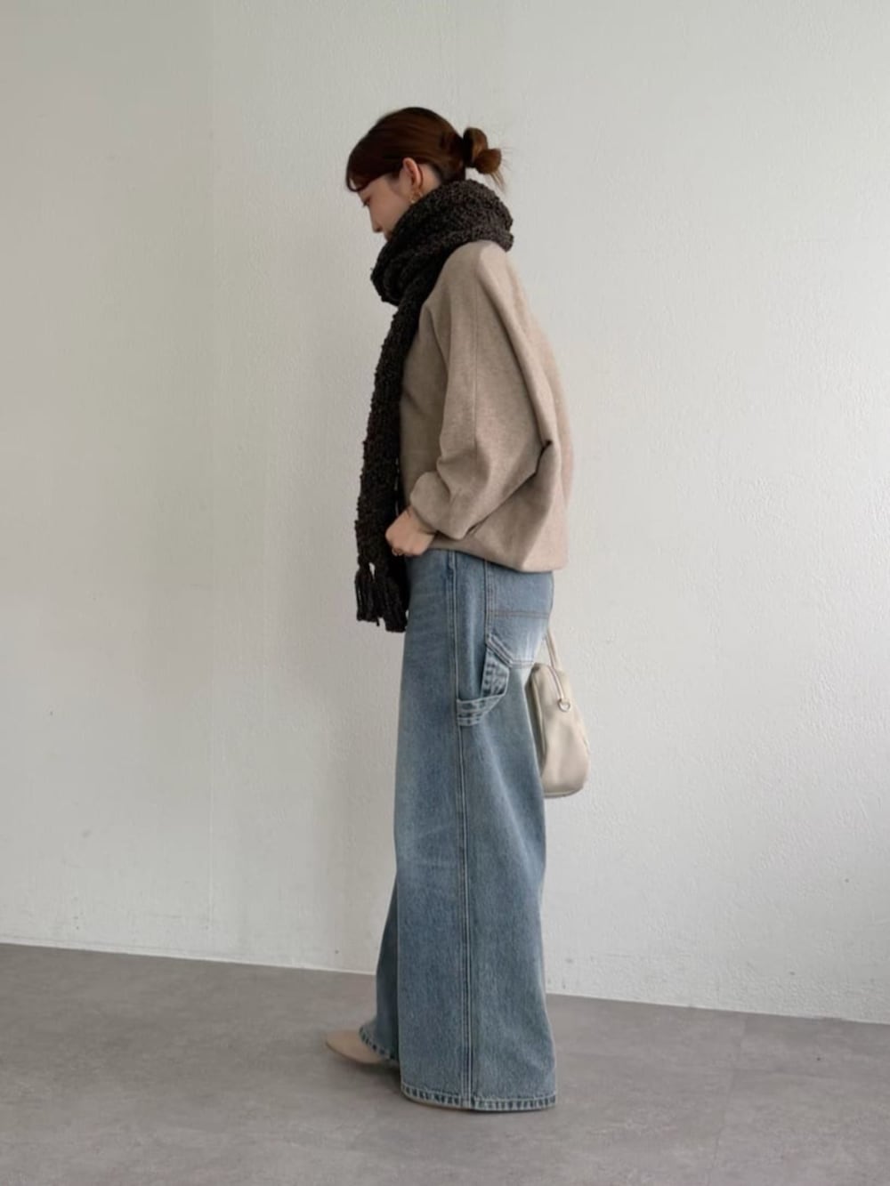ブルー系のデニムパンツ、ブラウン系のニット/セーター、ブラウン系のマフラーを着用したレディースの秋コーディネートの3枚目の写真