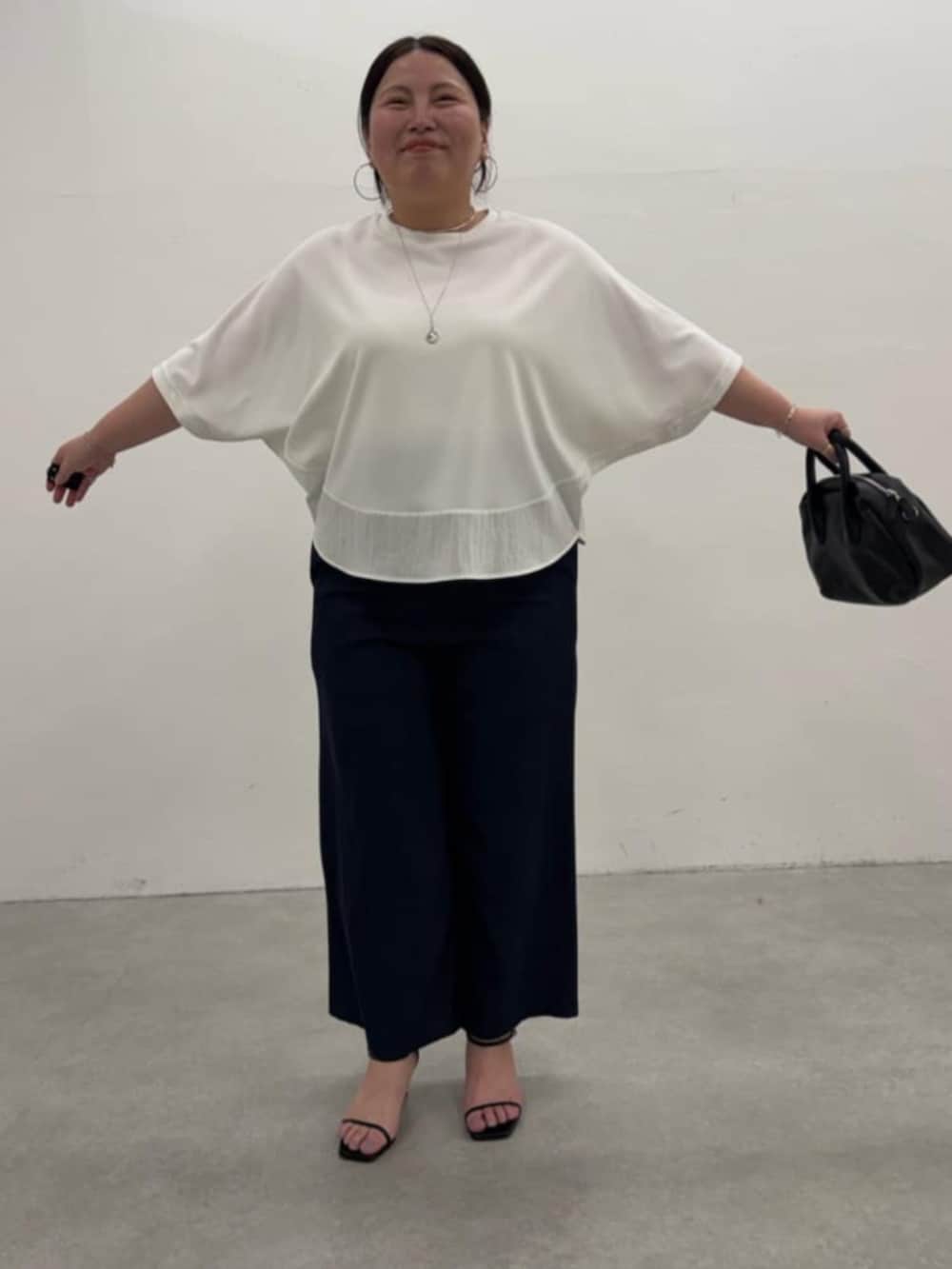 ブラック系のボストンバッグ、ブルー系のその他パンツ、ホワイト系のTシャツ/カットソーを着用したレディースの春コーディネートの6枚目の写真