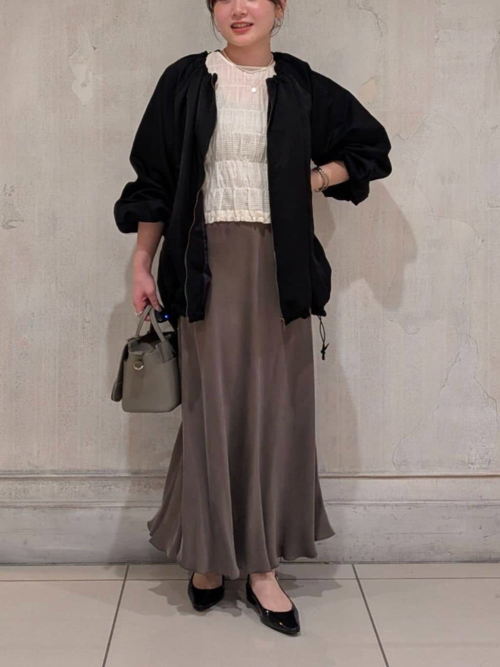 グリーン系のスカート、グレー系のハンドバッグ、ブラック系のノーカラージャケットを着用したレディースの春コーディネートの8枚目の写真
