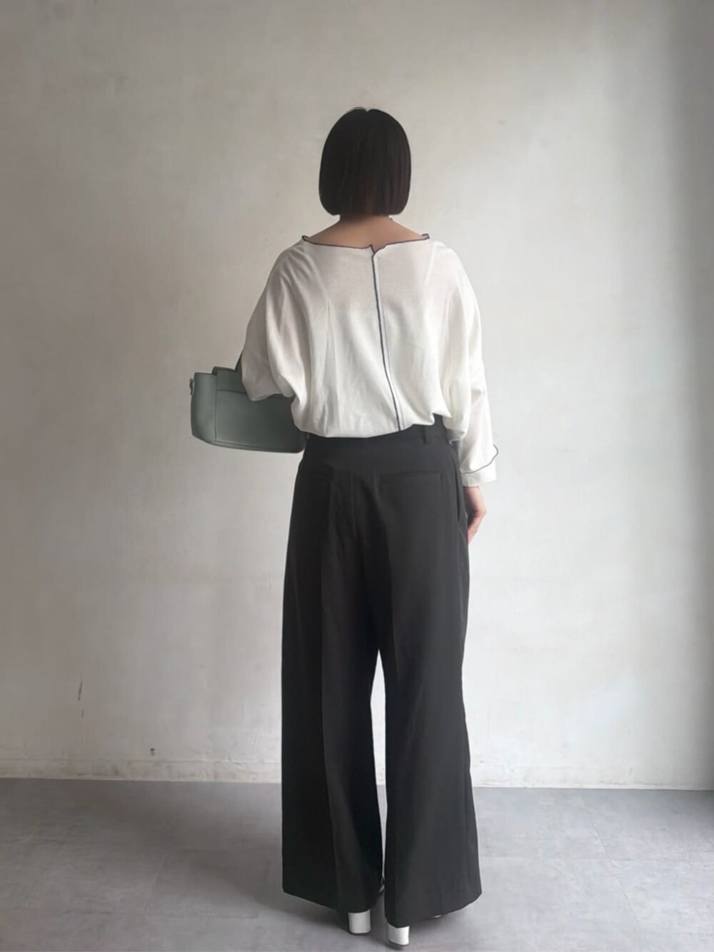 グリーン系のハンドバッグ、グレー系のその他パンツ、ホワイト系のTシャツ/カットソーを着用したレディースの冬コーディネートの4枚目の写真