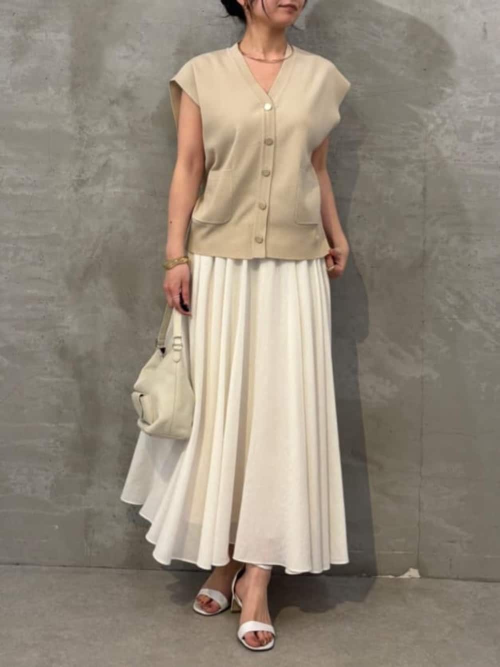 ホワイト系のスカート、ベージュ系のカーディガン/ボレロを着用したレディースの春コーディネートの2枚目の写真