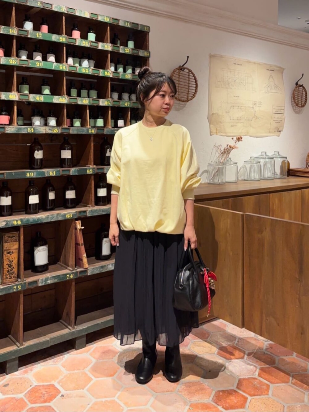 ブラック系のボストンバッグ、ブラック系のその他パンツ、イエロー系のTシャツ/カットソーを着用したレディースの冬コーディネートの3枚目の写真