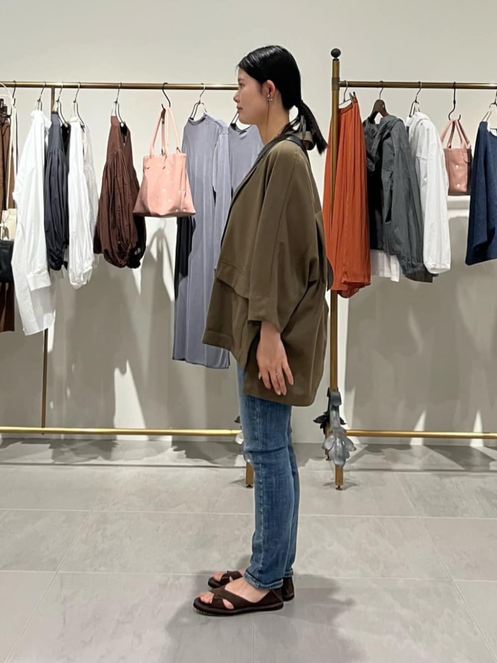 ブルー系のデニムパンツ、ブラック系のショルダーバッグ、ブラウン系のテーラードジャケットを着用したレディースの春コーディネートの7枚目の写真