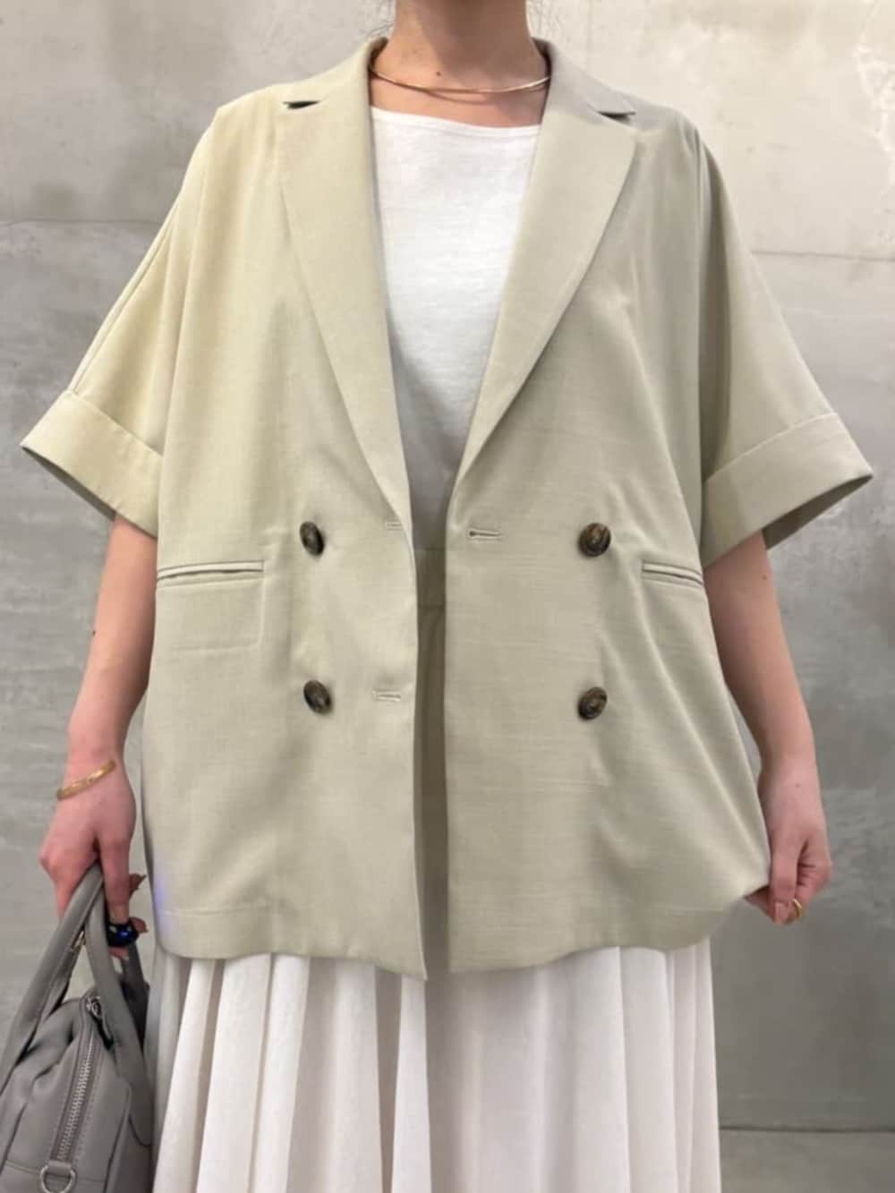 グレー系のボストンバッグ、ホワイト系のキャミソール、ベージュ系のテーラードジャケットを着用したレディースの春コーディネートの5枚目の写真