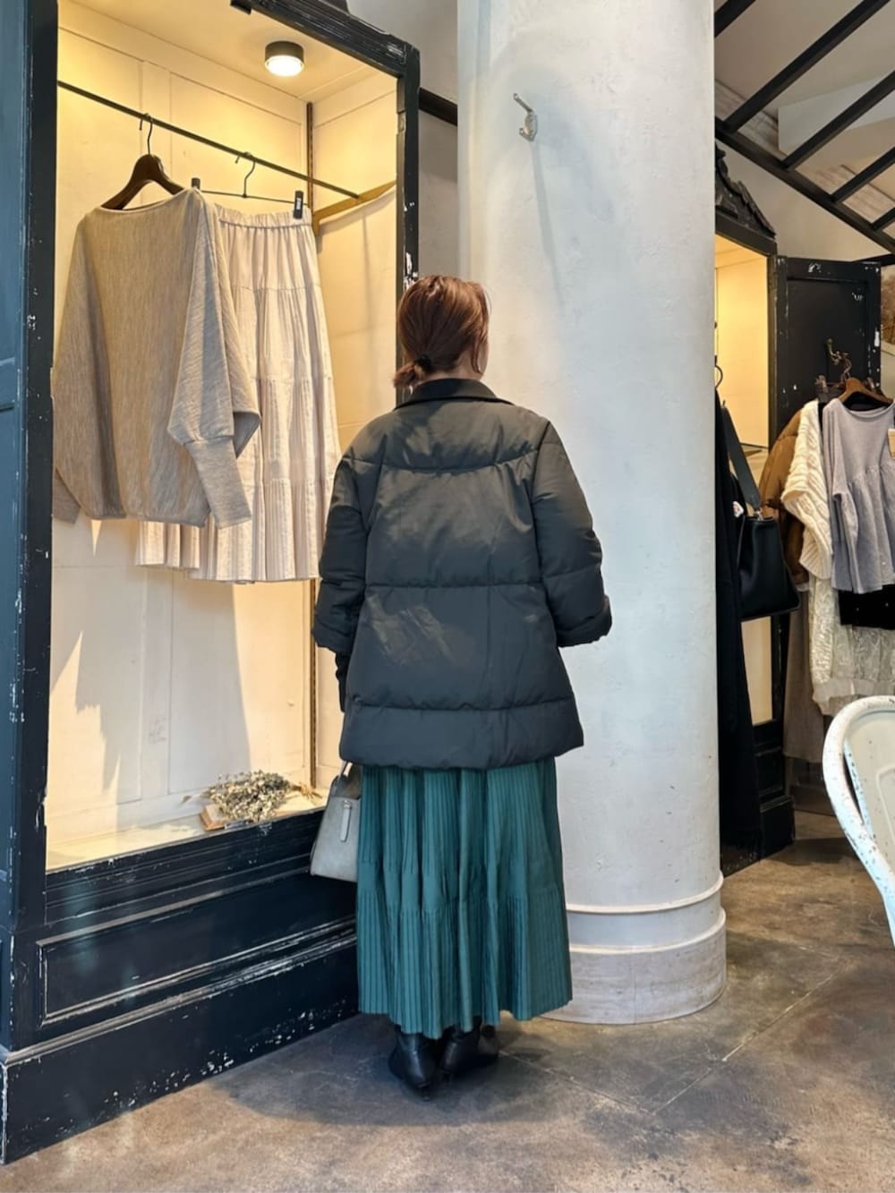グリーン系のスカート、グレー系のニット/セーター、ブラック系のダウンジャケット/コートを着用したレディースの冬コーディネートの4枚目の写真