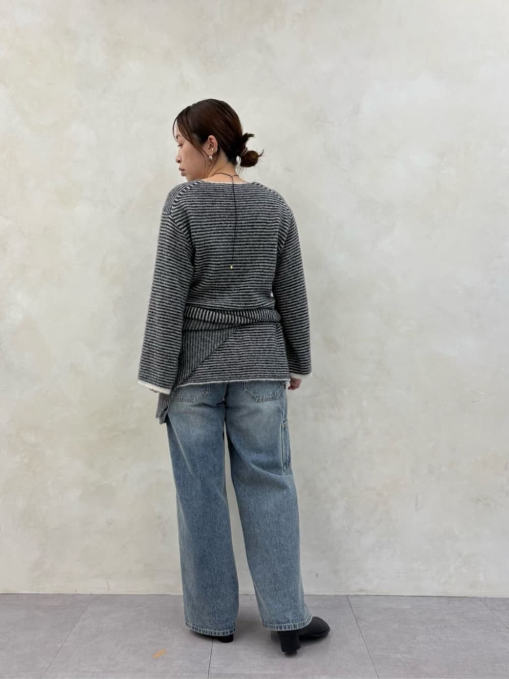 ブルー系のデニムパンツ、ブラック系のブーツ、ブラック系のニット/セーターを着用したレディースの秋コーディネートの7枚目の写真