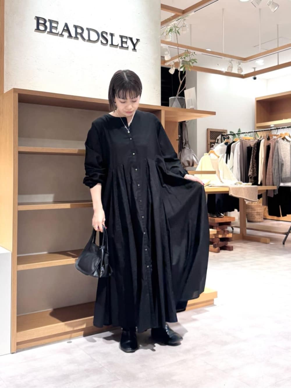 ブルー系のデニムパンツ、イエロー系のトートバッグ、ブラック系のワンピースを着用したレディースの冬コーディネートの8枚目の写真