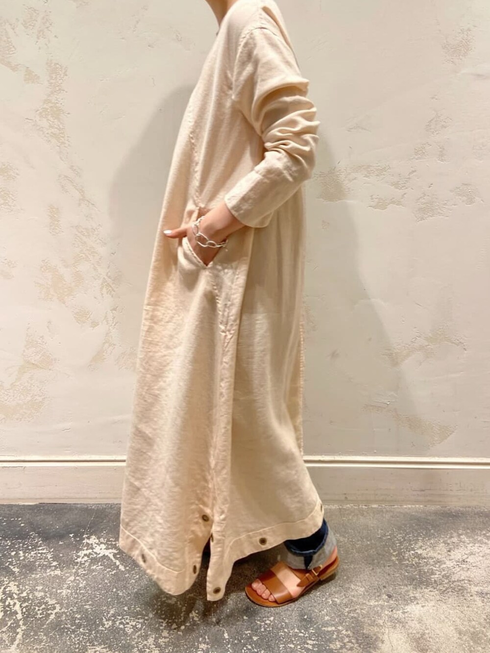 ホワイト系のワンピース、イエロー系のトートバッグ、ブルー系のデニムパンツを着用したレディースの春コーディネートの2枚目の写真