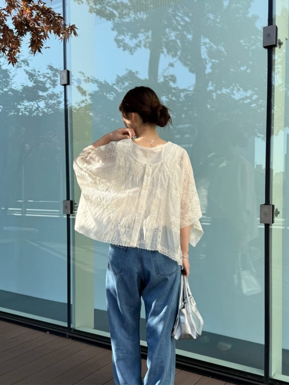 ブルー系のデニムパンツ、シルバー系のトートバッグ、ベージュ系のシャツ/ブラウスを着用したレディースの冬コーディネートの2枚目の写真