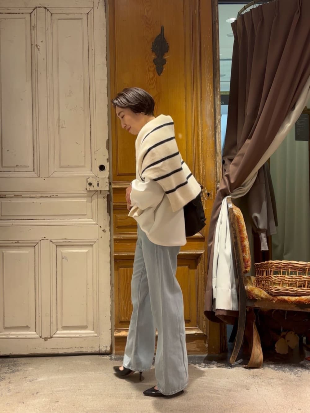 ブルー系のデニムパンツ、ホワイト系のTシャツ/カットソー、ブラック系のショルダーバッグを着用したレディースの冬コーディネートの6枚目の写真