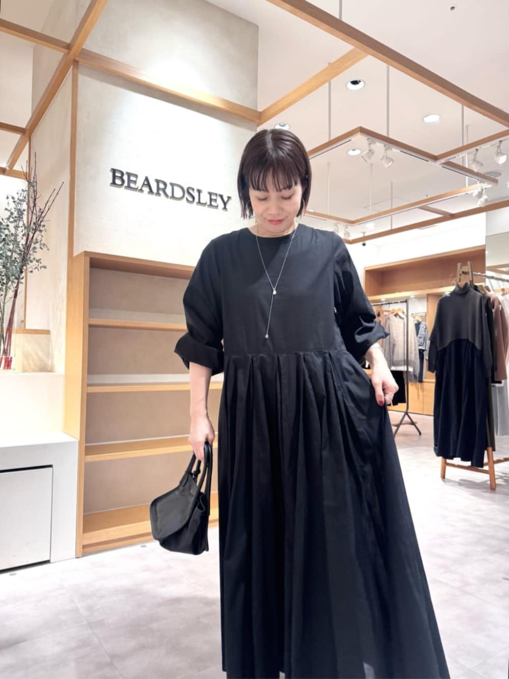 ブルー系のデニムパンツ、イエロー系のトートバッグ、ブラック系のワンピースを着用したレディースの冬コーディネートの9枚目の写真