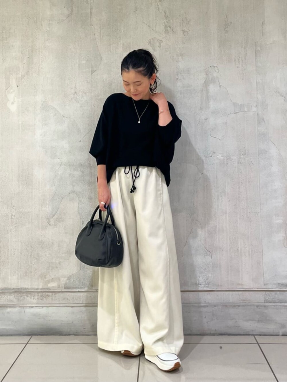 ブラック系のニット/セーター、ホワイト系のその他パンツを着用したレディースの冬コーディネートの2枚目の写真