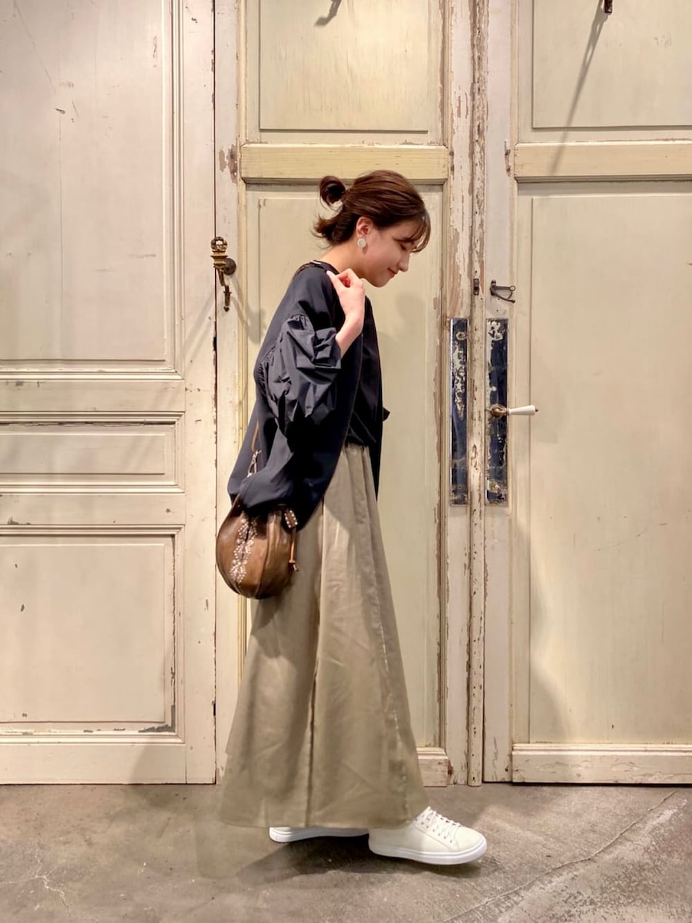 グリーン系のスカート、グリーン系のショルダーバッグを着用したレディースの秋コーディネートの2枚目の写真