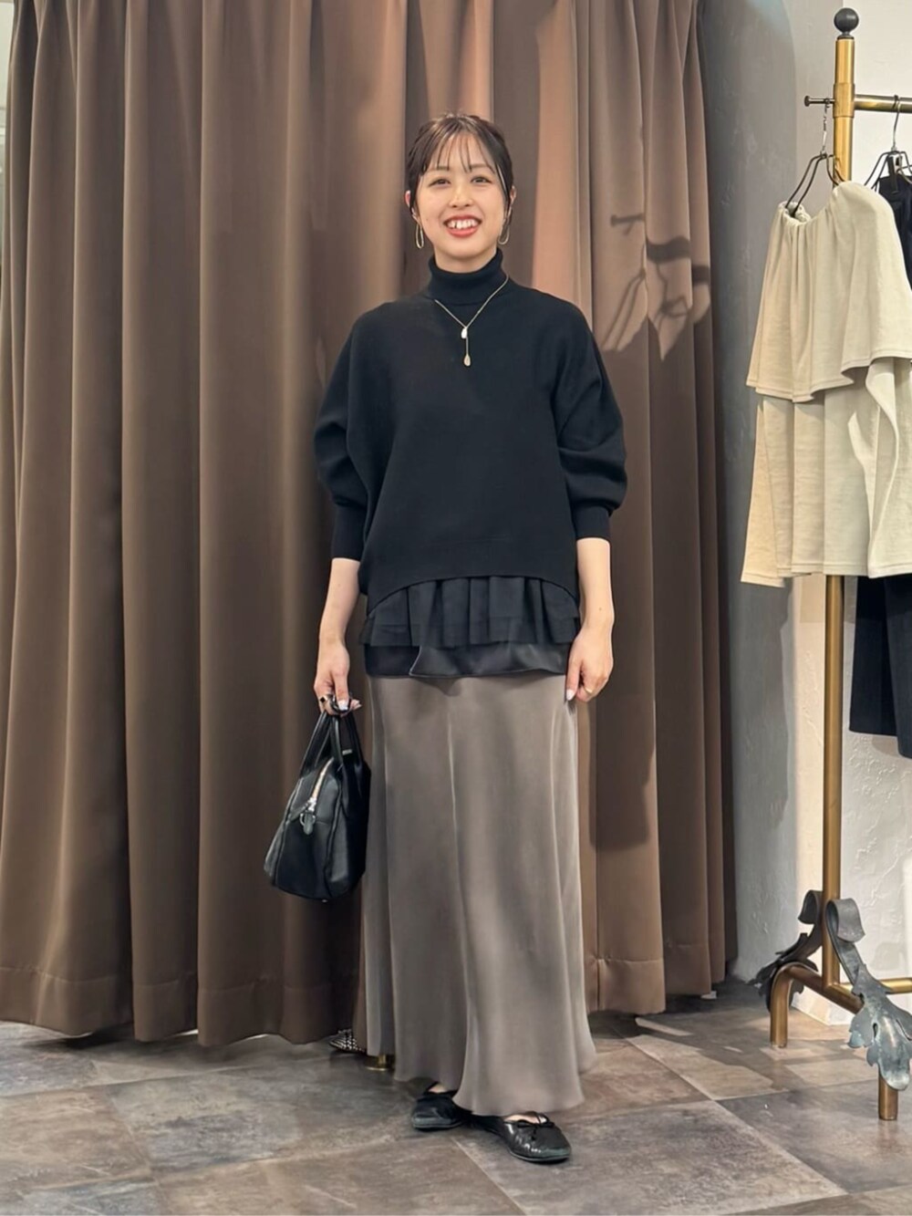 グリーン系のスカート、ブラック系のボストンバッグ、ブラック系のニット/セーターを着用したレディースの冬コーディネートの3枚目の写真