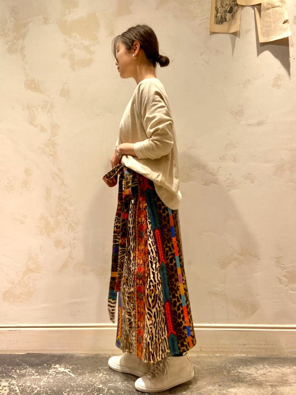 ベージュ系のトートバッグ、ホワイト系のニット/セーター、ホワイト系のスニーカーを着用したレディースの春コーディネートの2枚目の写真