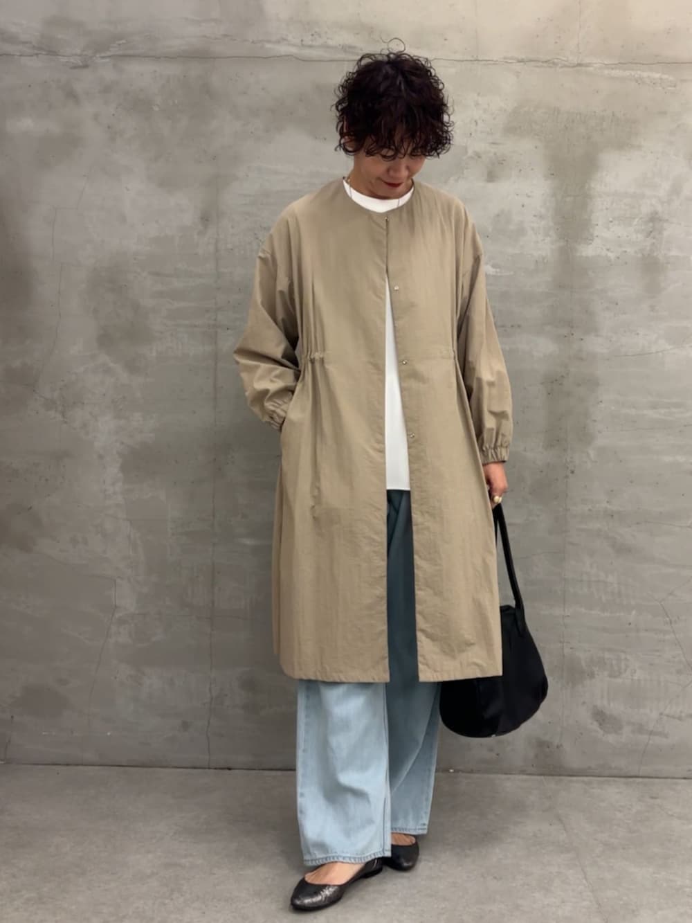 ベージュ系のその他アウター、ブラック系のボストンバッグ、ブルー系のデニムパンツを着用したレディースの冬コーディネートの4枚目の写真