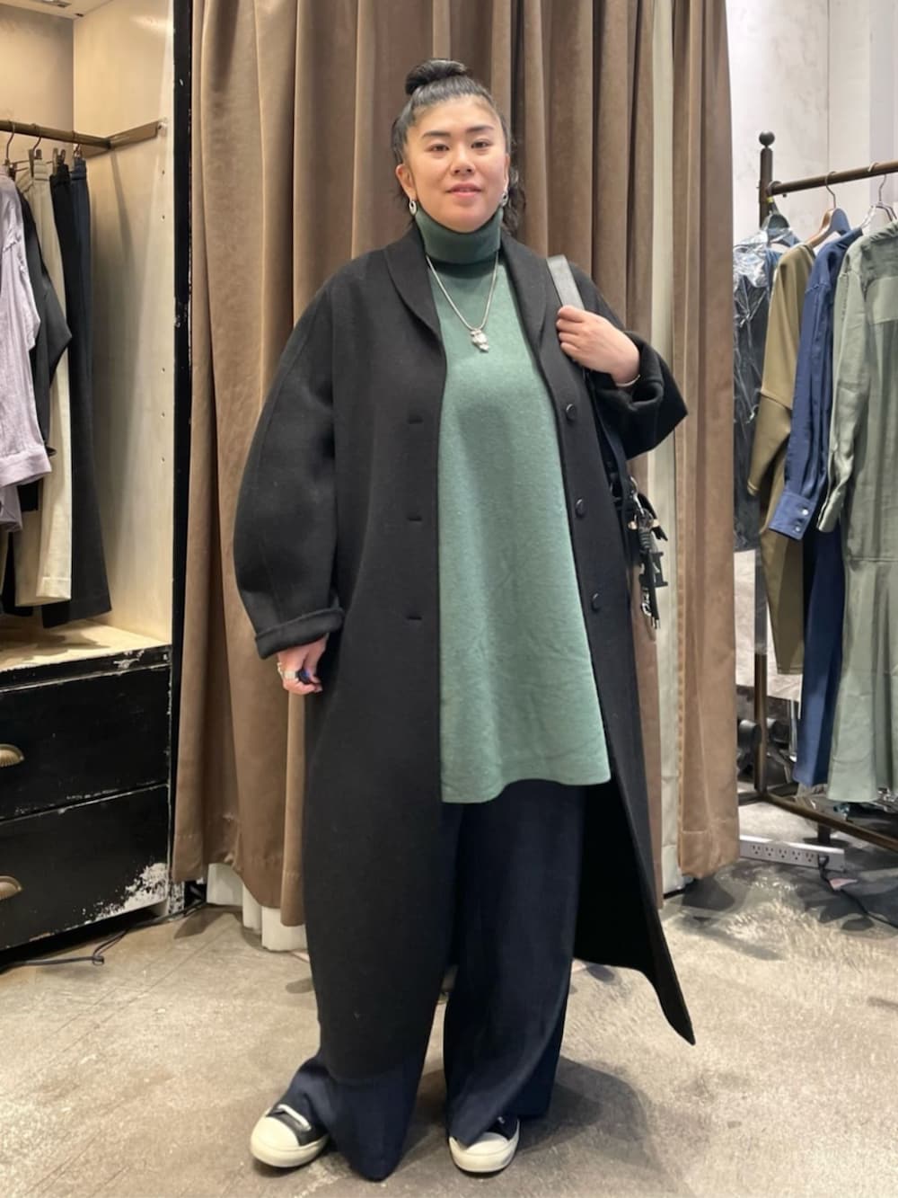 ブラック系のショルダーバッグ、ブラック系のその他アウター、グリーン系のニット/セーターを着用したレディースの冬コーディネートの2枚目の写真