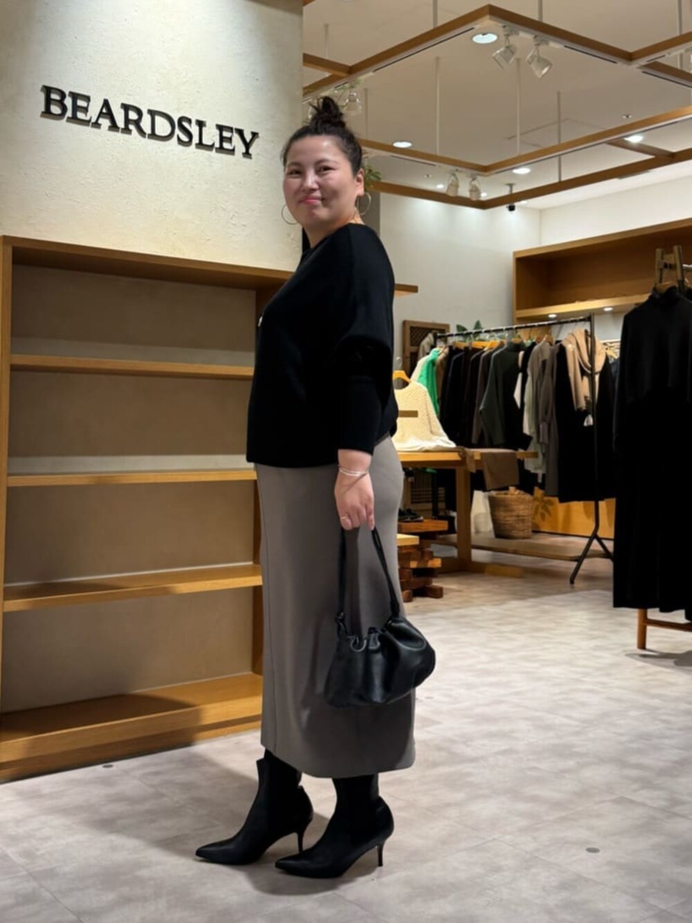 ブラック系のニット/セーター、ブラック系のブーツ、ブラウン系のスカートを着用したレディースの冬コーディネートの4枚目の写真