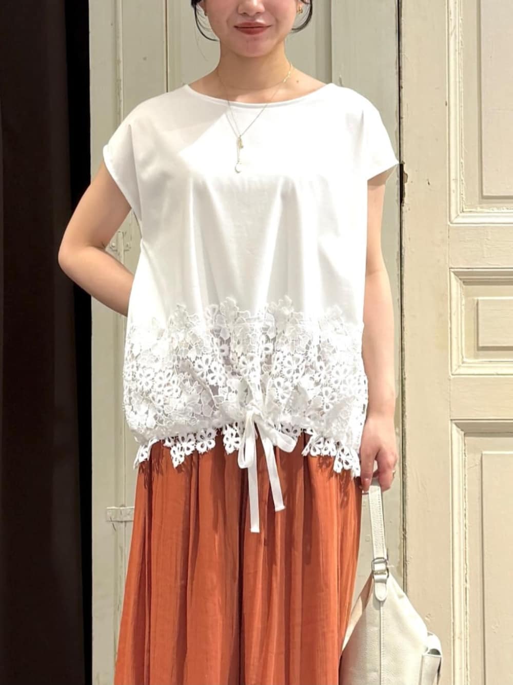 ホワイト系のトートバッグ、オレンジ系のその他パンツ、ホワイト系のTシャツ/カットソーを着用したレディースの春コーディネートの4枚目の写真