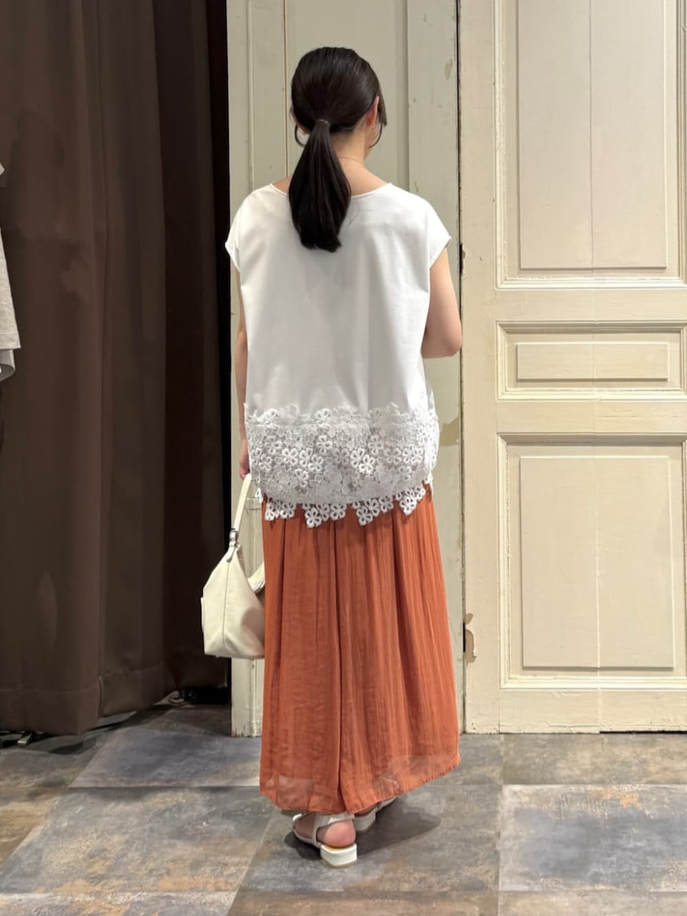 ホワイト系のトートバッグ、オレンジ系のその他パンツ、ホワイト系のTシャツ/カットソーを着用したレディースの春コーディネートの3枚目の写真