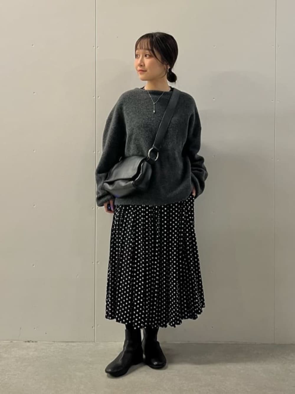 ブラック系のワンピース、ブラック系のブーツ、グレー系のニット/セーターを着用したレディースの冬コーディネートの2枚目の写真