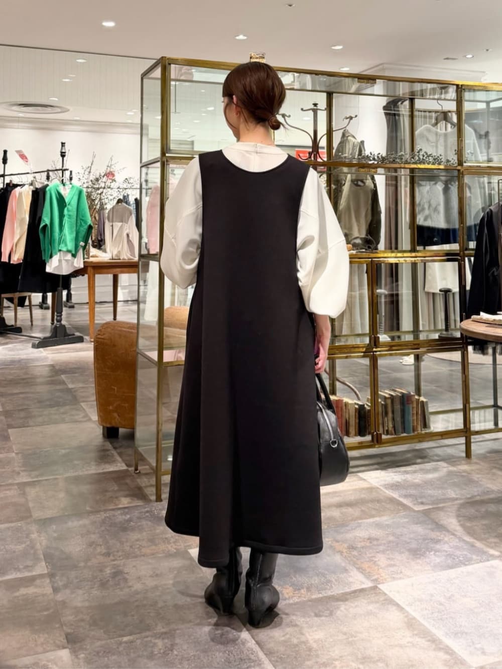 ブラック系のボストンバッグ、ホワイト系のシャツ/ブラウス、ブラック系のジャンパースカートを着用したレディースの冬コーディネートの3枚目の写真