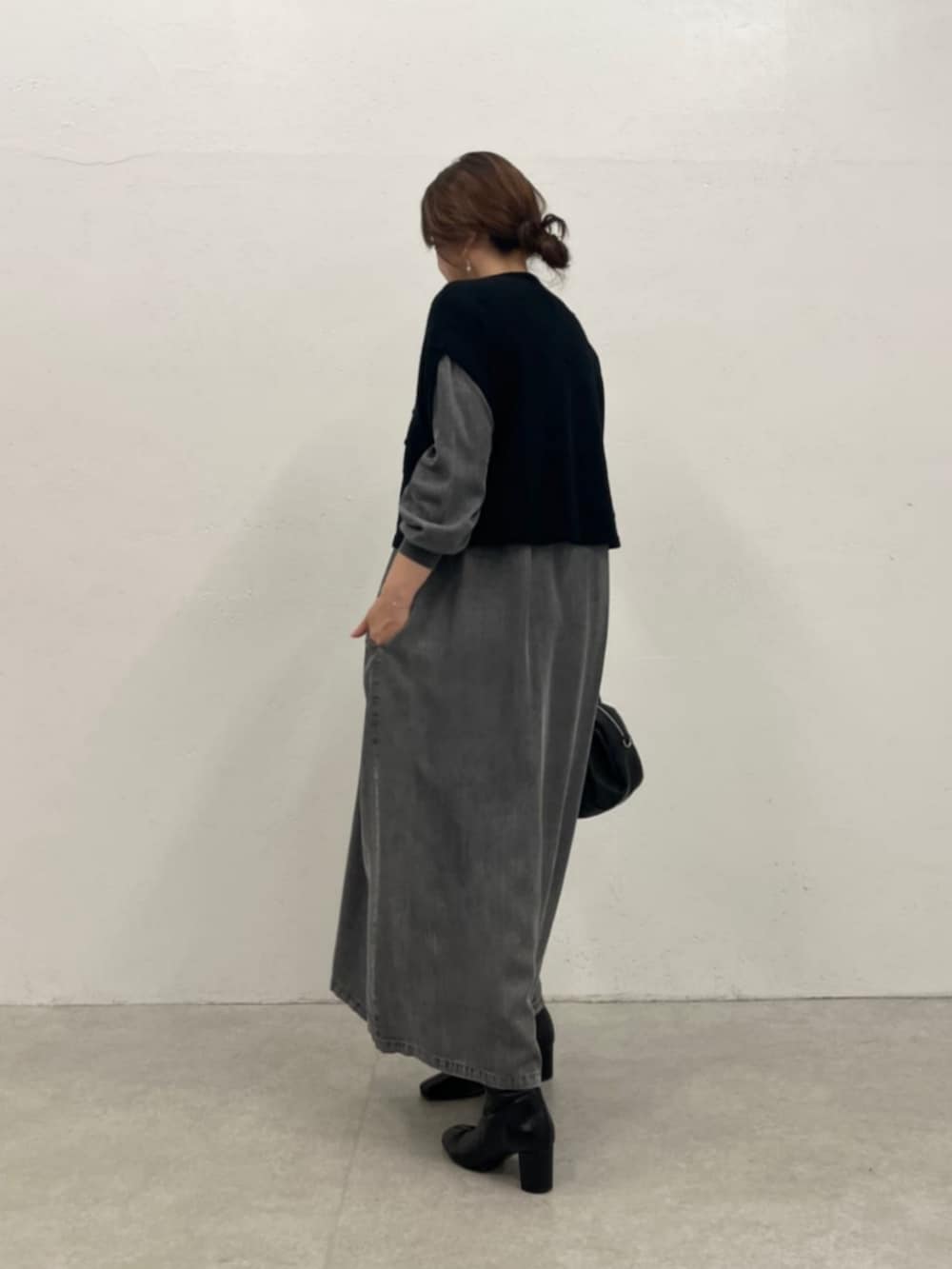 グレー系のワンピース、ブラック系のベストを着用したレディースの秋コーディネートの3枚目の写真