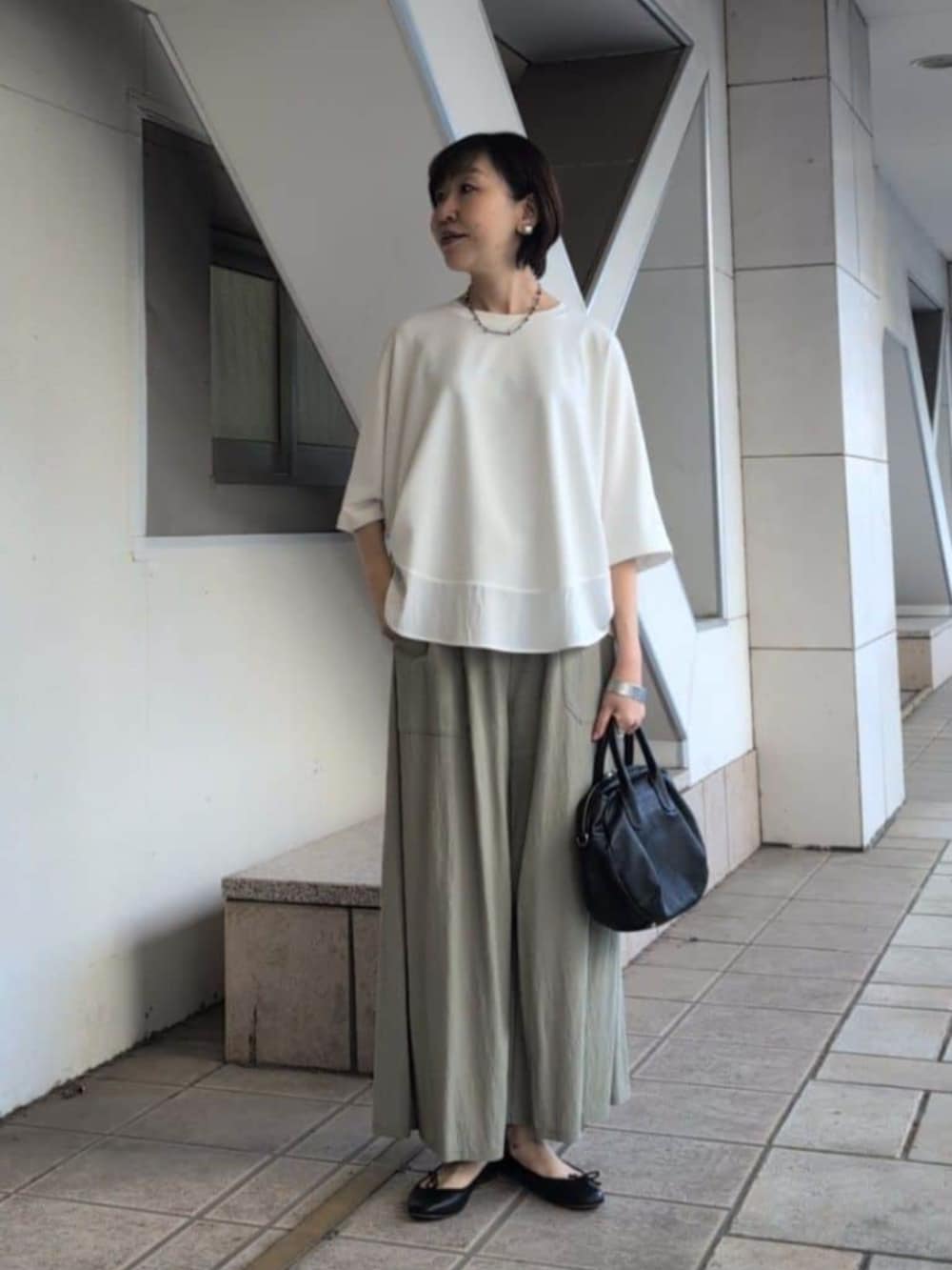 ブラック系のボストンバッグ、グリーン系のその他パンツ、ホワイト系のTシャツ/カットソーを着用したレディースの春コーディネートの5枚目の写真