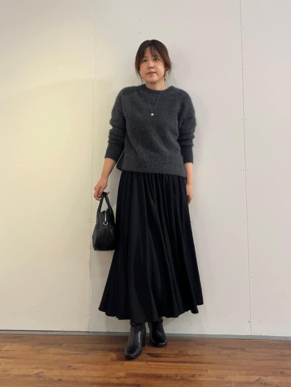 ブラック系のスカート、グレー系のニット/セーターを着用したレディースの秋コーディネートの2枚目の写真