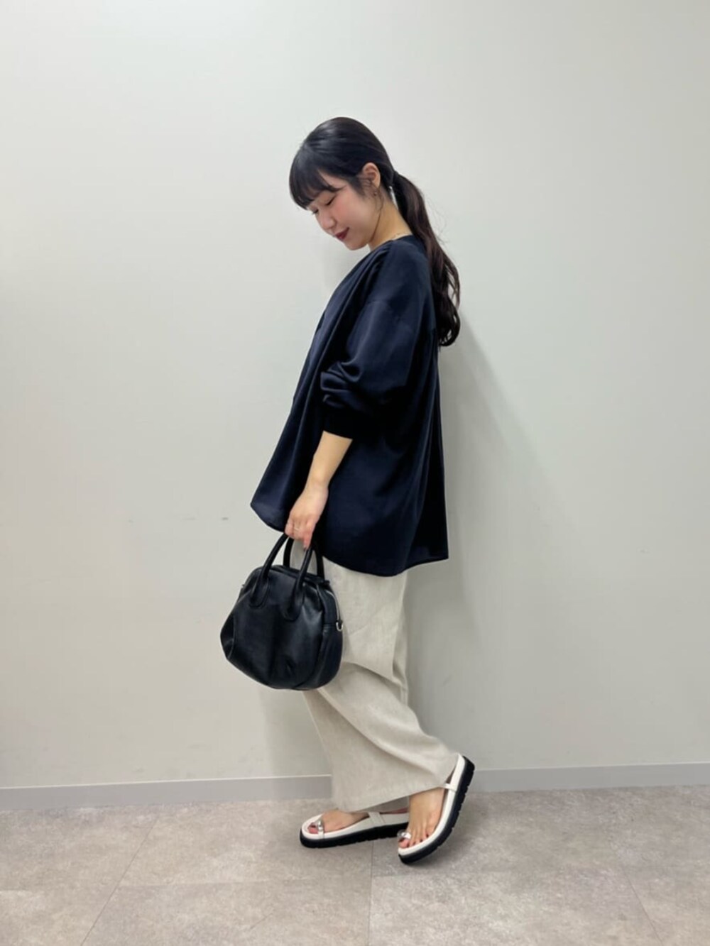 ブラック系のボストンバッグ、ホワイト系のサンダル、ブルー系のシャツ/ブラウスを着用したレディースの春コーディネートの4枚目の写真