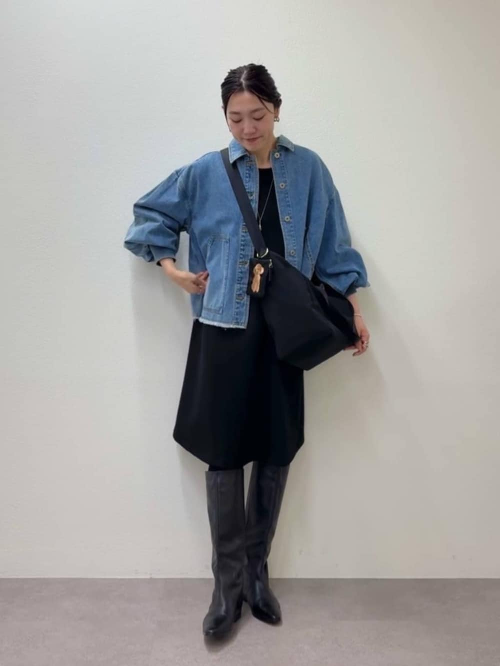 ブルー系のデニムジャケット、ブラック系のワンピース、ブラック系のトートバッグを着用したレディースの冬コーディネートの2枚目の写真