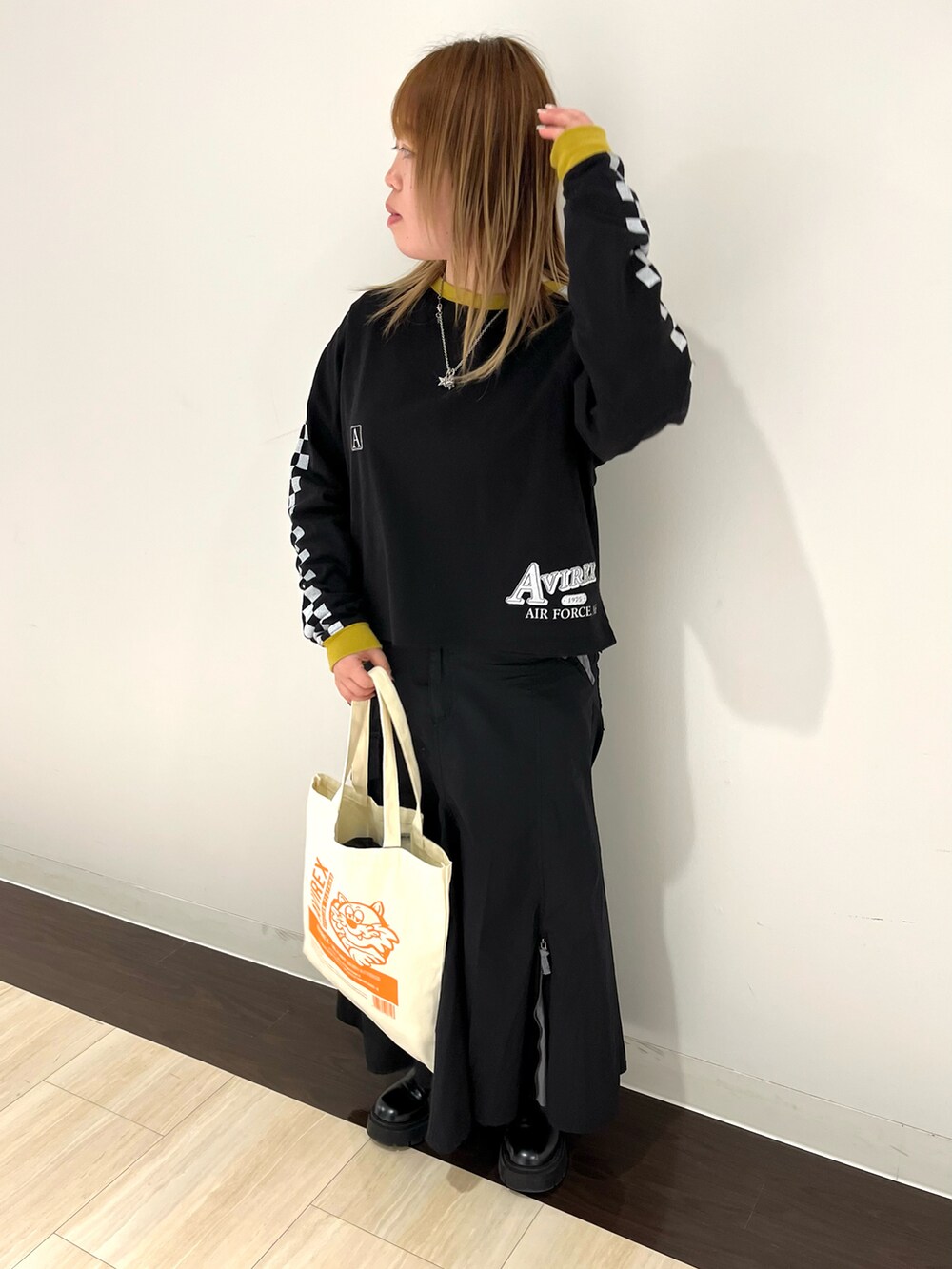 ブラック系のTシャツ/カットソー、ホワイト系のトートバッグ、グリーン系のスカートを着用したレディースの春コーディネートの2枚目の写真
