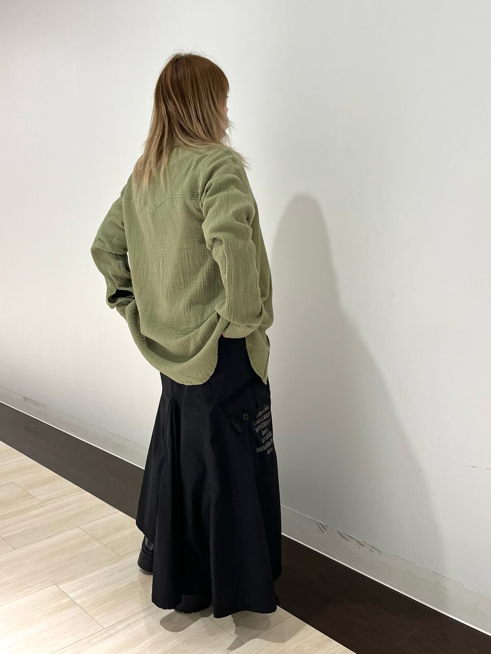 オレンジ系のシャツ/ブラウス、グリーン系のスカート、ベージュ系のTシャツ/カットソーを着用したレディースの春コーディネートの3枚目の写真