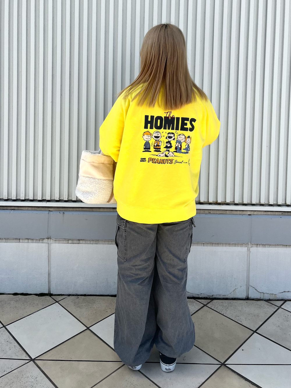 イエロー系のスウェット、ホワイト系のトートバッグ、ブラック系のデニムパンツを着用したレディースの秋コーディネートの2枚目の写真