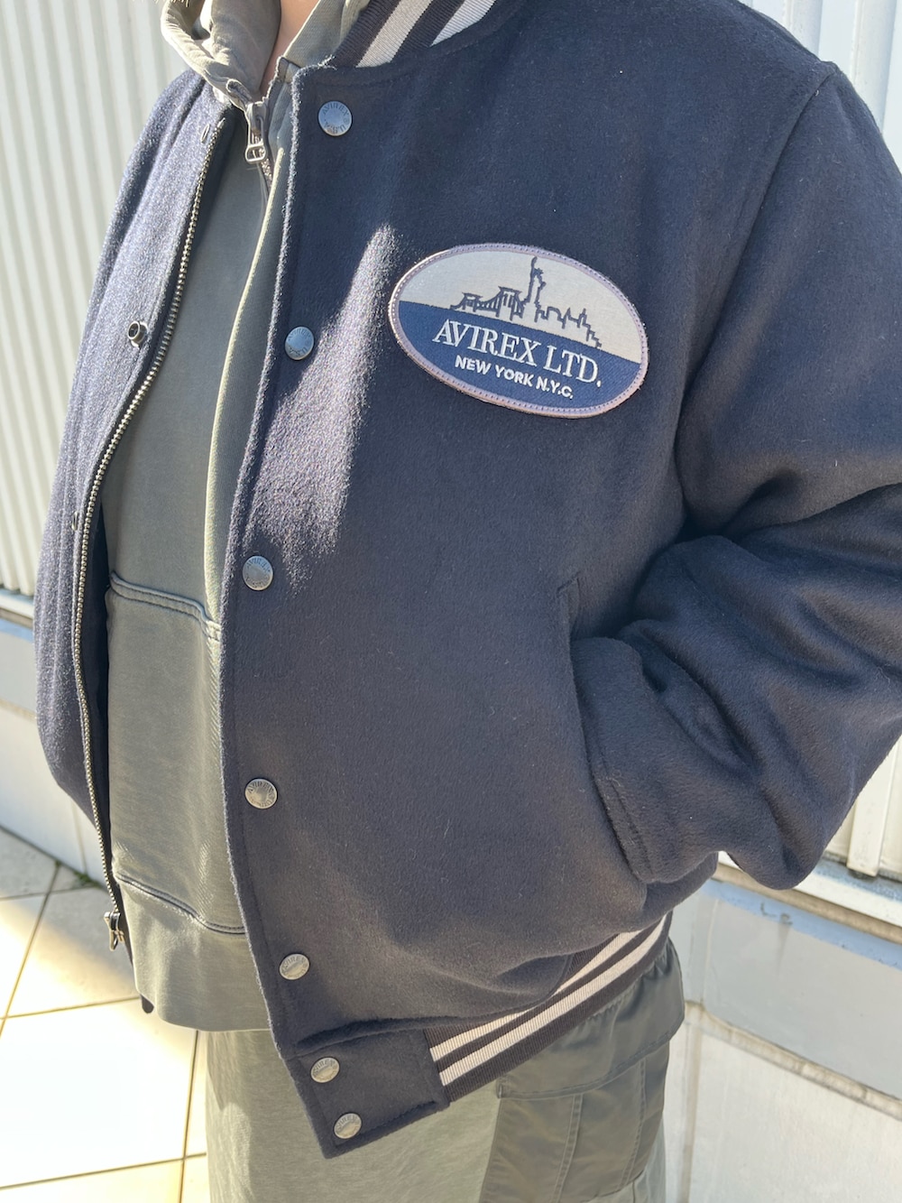 グレー系のパーカー、ブルー系のスタジャン、グレー系のスカートを着用したレディースの冬コーディネートの4枚目の写真