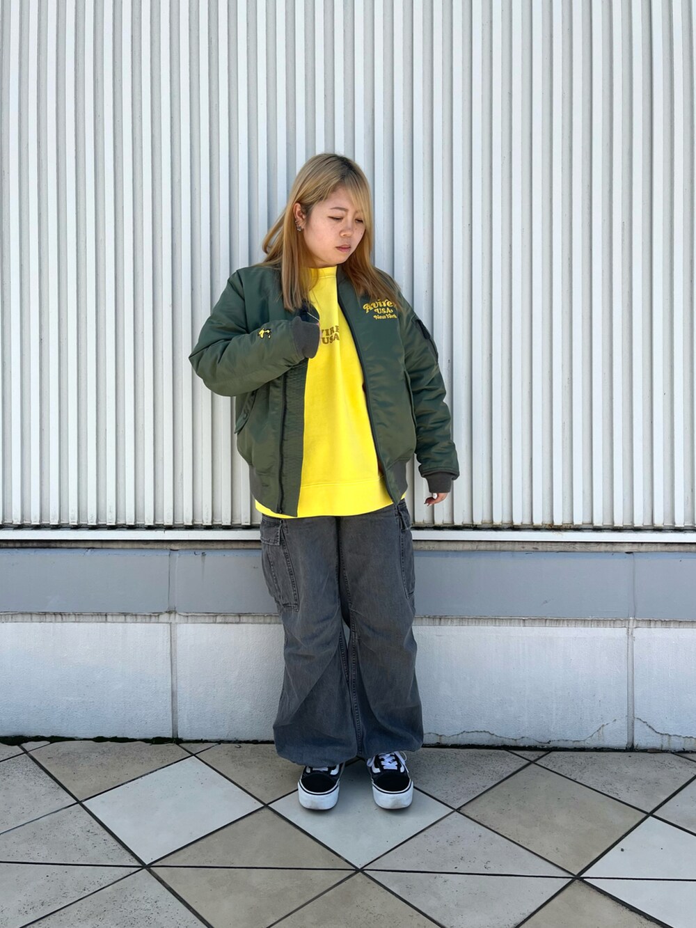 グリーン系のMA-1、イエロー系のスウェット、ブラック系のデニムパンツを着用したレディースの秋コーディネートの2枚目の写真