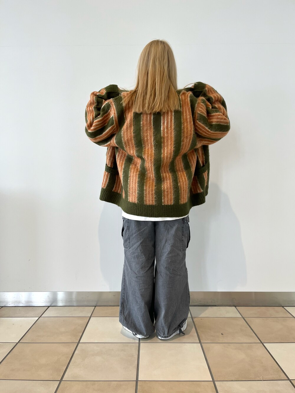 グリーン系のカーディガン/ボレロ、ホワイト系のTシャツ/カットソー、ブルー系のデニムパンツを着用したレディースの秋コーディネートの2枚目の写真