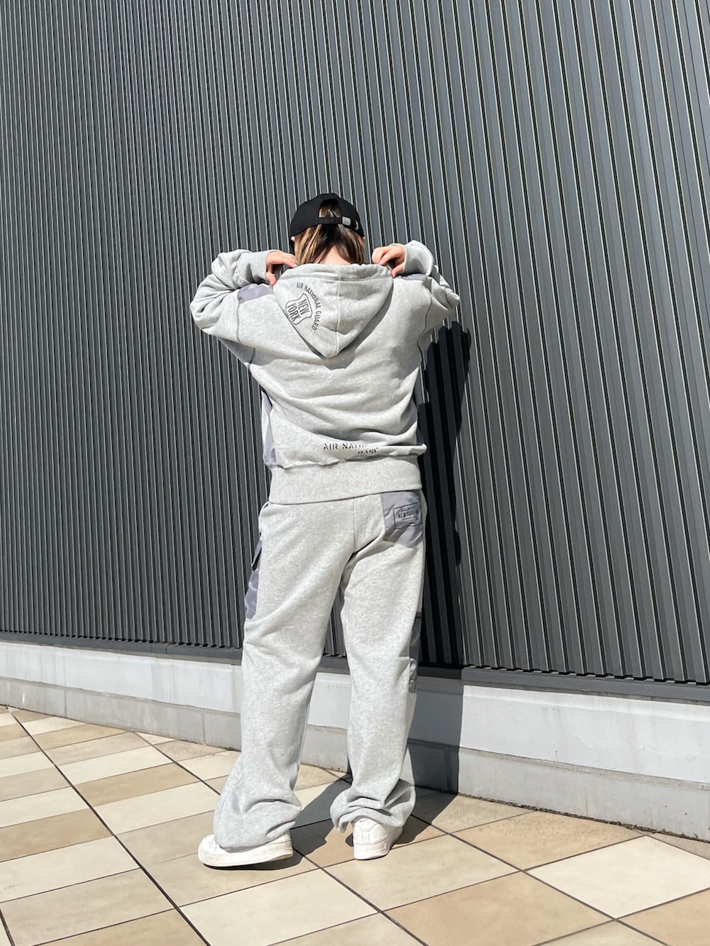 グレー系のパーカー、グレー系のスウェットパンツ、ブラック系のキャップを着用したレディースの夏コーディネートの2枚目の写真