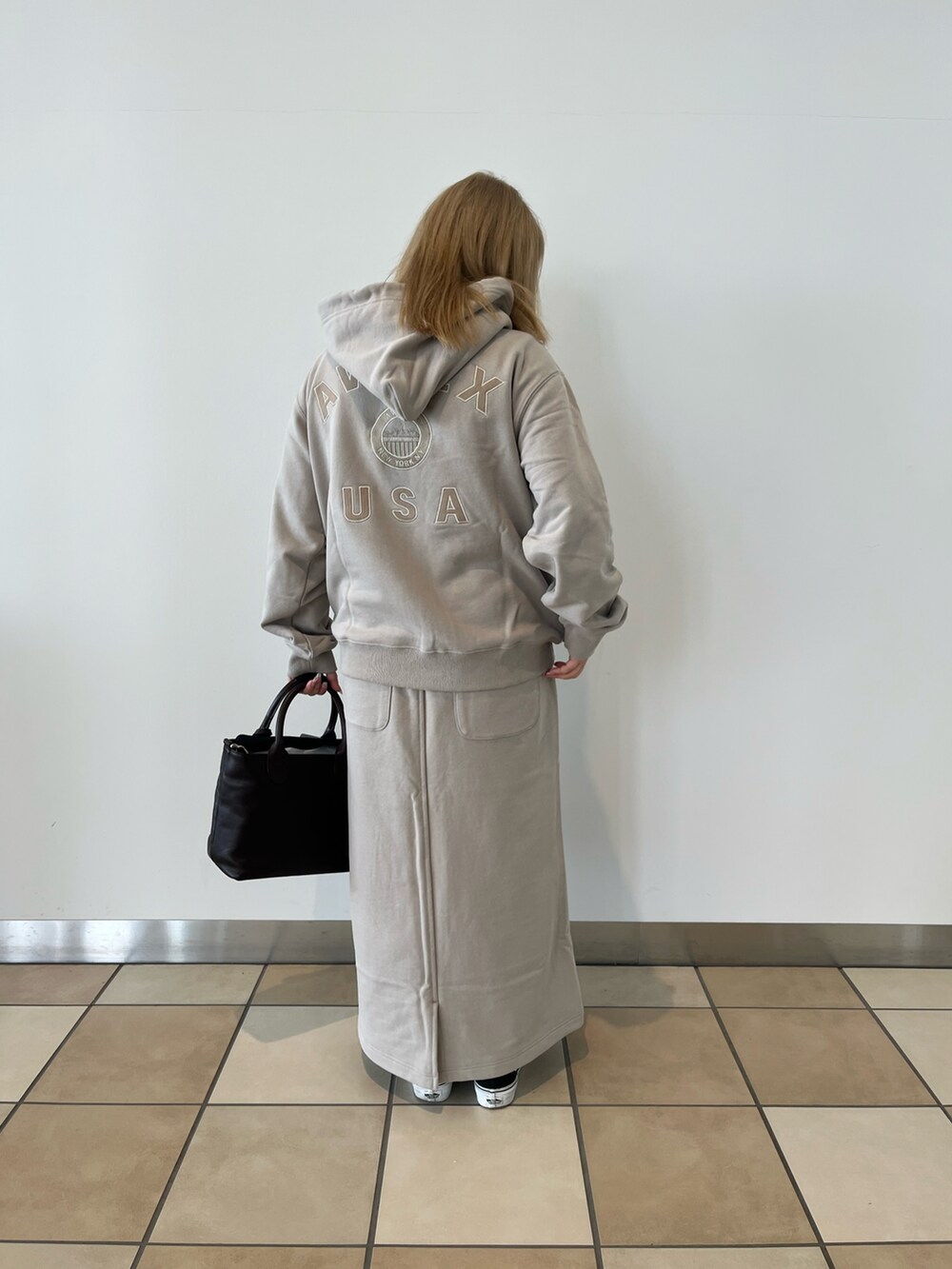 ベージュ系のパーカー、ベージュ系のスカート、ブラウン系のトートバッグを着用したレディースの秋コーディネートの2枚目の写真