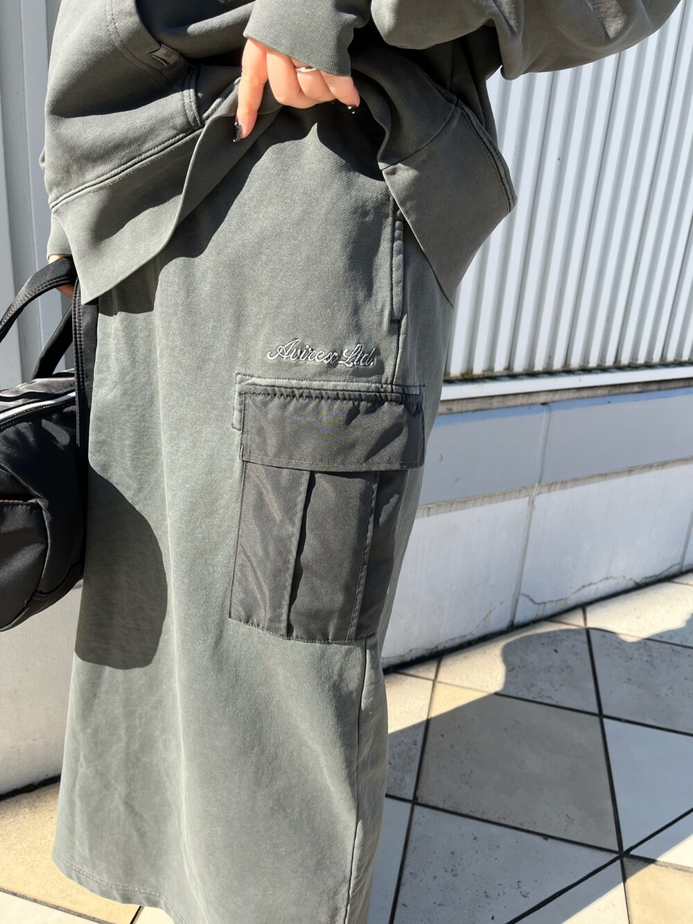 グレー系のパーカー、グレー系のスカート、ブラック系のボストンバッグを着用したレディースの冬コーディネートの4枚目の写真