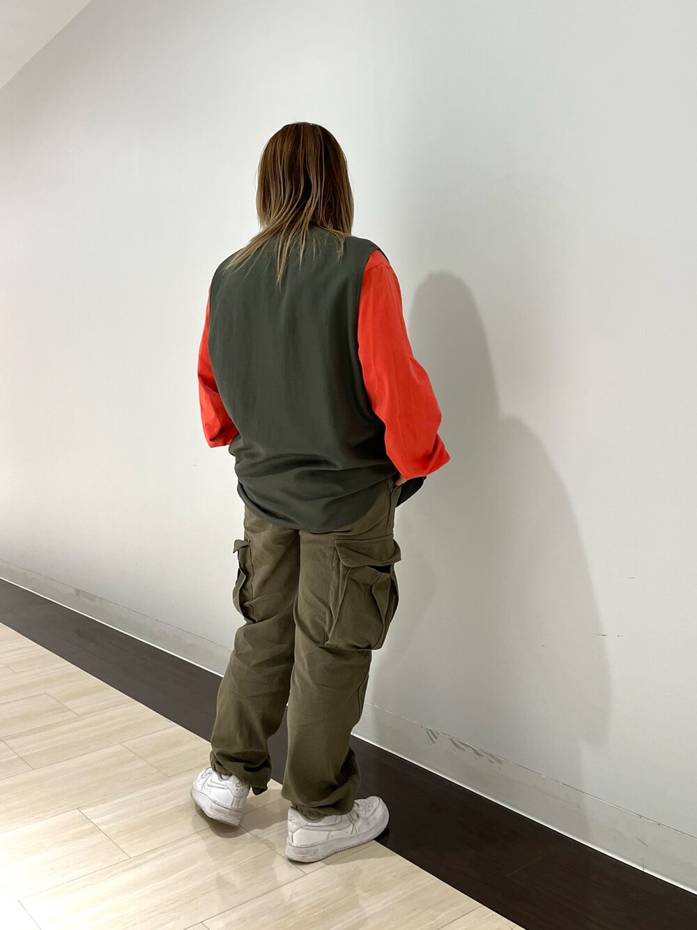 グリーン系のベスト、オレンジ系のTシャツ/カットソー、グリーン系のカーゴパンツを着用したレディースの春コーディネートの2枚目の写真