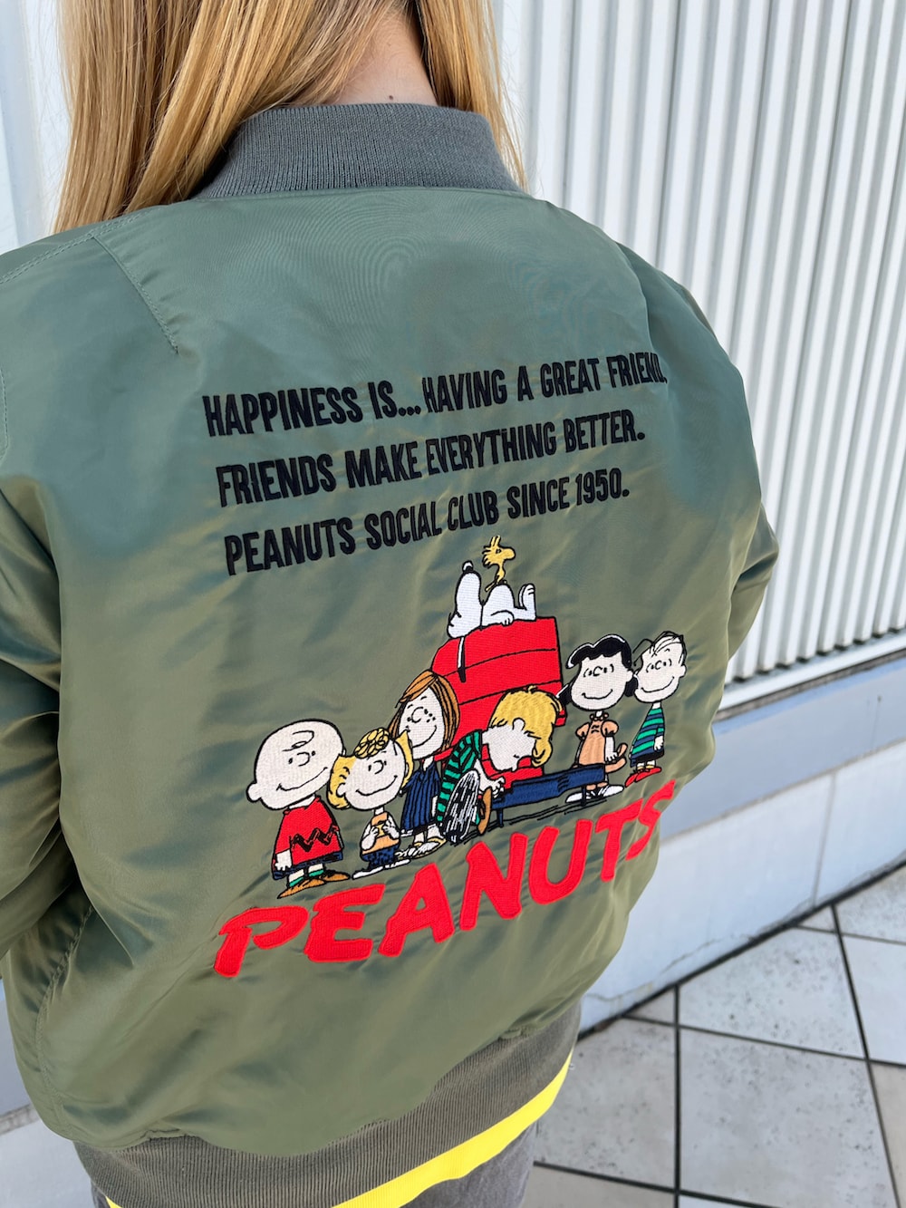 グリーン系のMA-1、イエロー系のスウェット、ブラック系のデニムパンツを着用したレディースの秋コーディネートの5枚目の写真