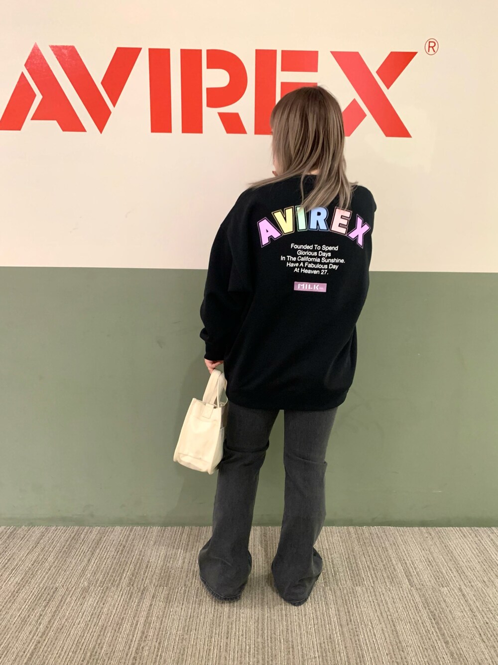 ブラック系のスウェット、ホワイト系のバッグ、ブラック系のデニムパンツを着用したレディースの秋コーディネートの2枚目の写真