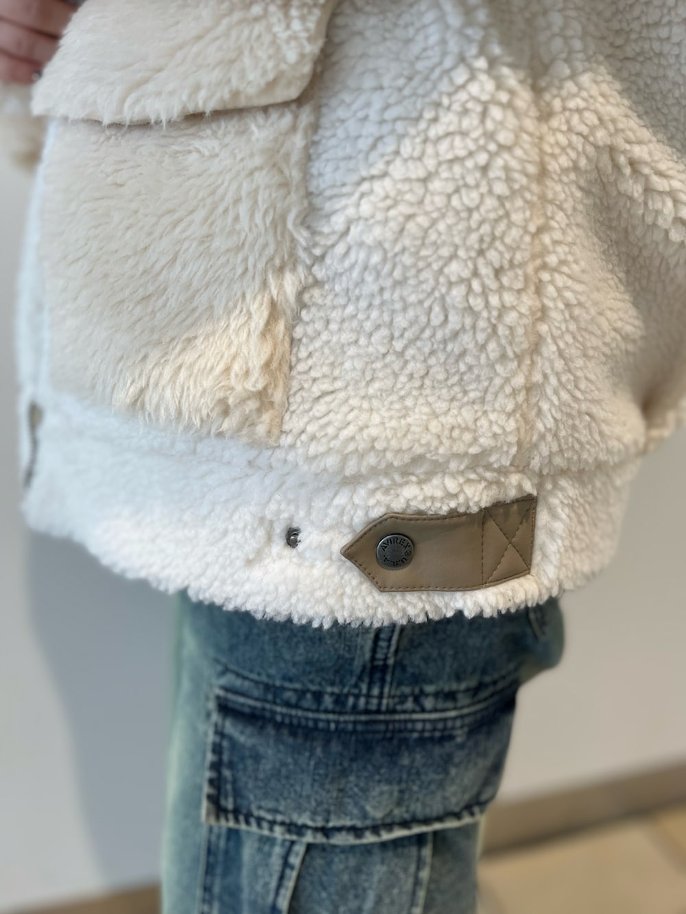 ホワイト系のブルゾン、ベージュ系のスウェット、ブルー系のデニムパンツを着用したレディースの秋コーディネートの5枚目の写真