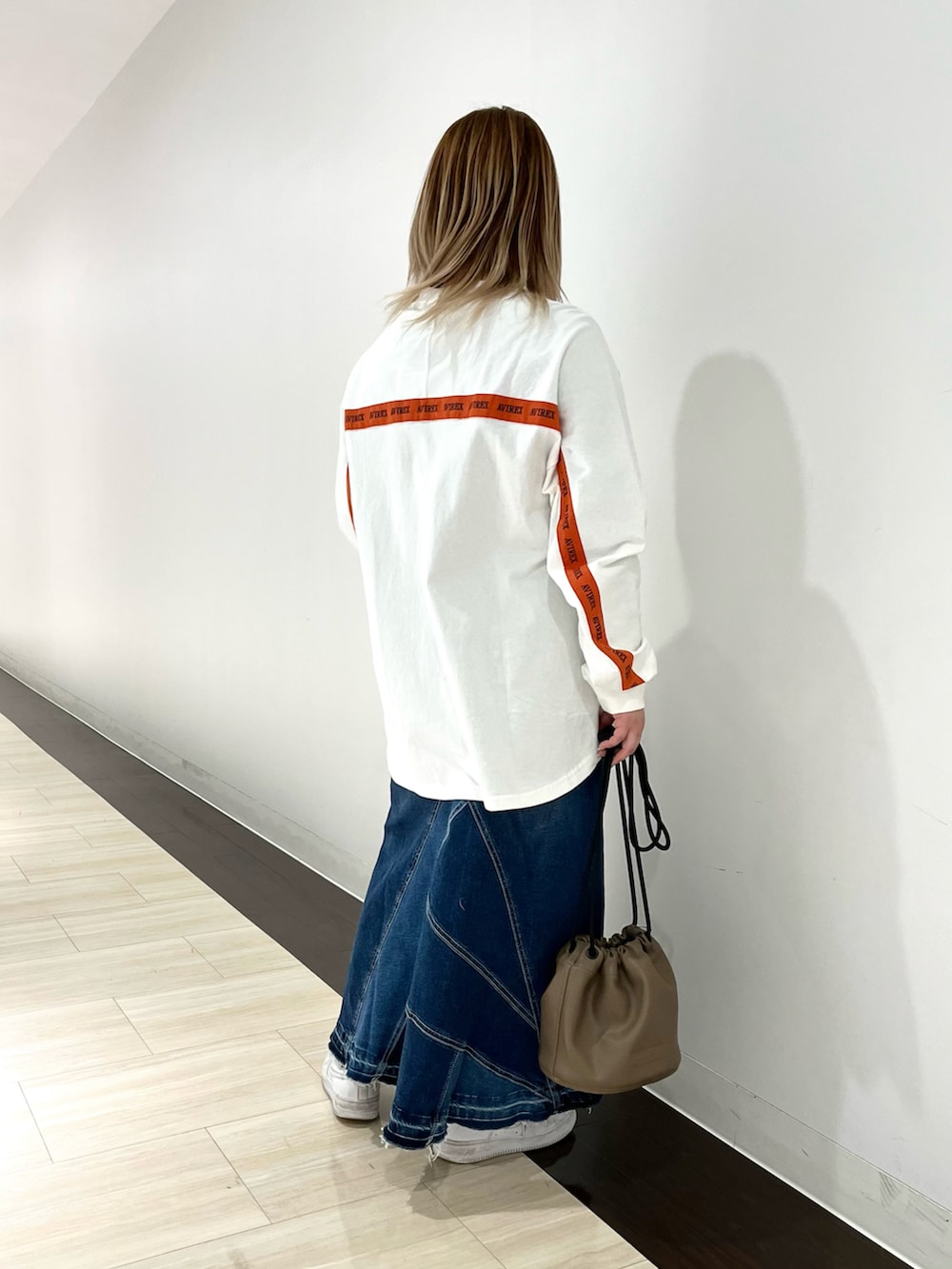 ホワイト系のTシャツ/カットソー、ブラック系のショルダーバッグ、ブルー系のデニムスカートを着用したレディースの春コーディネートの2枚目の写真