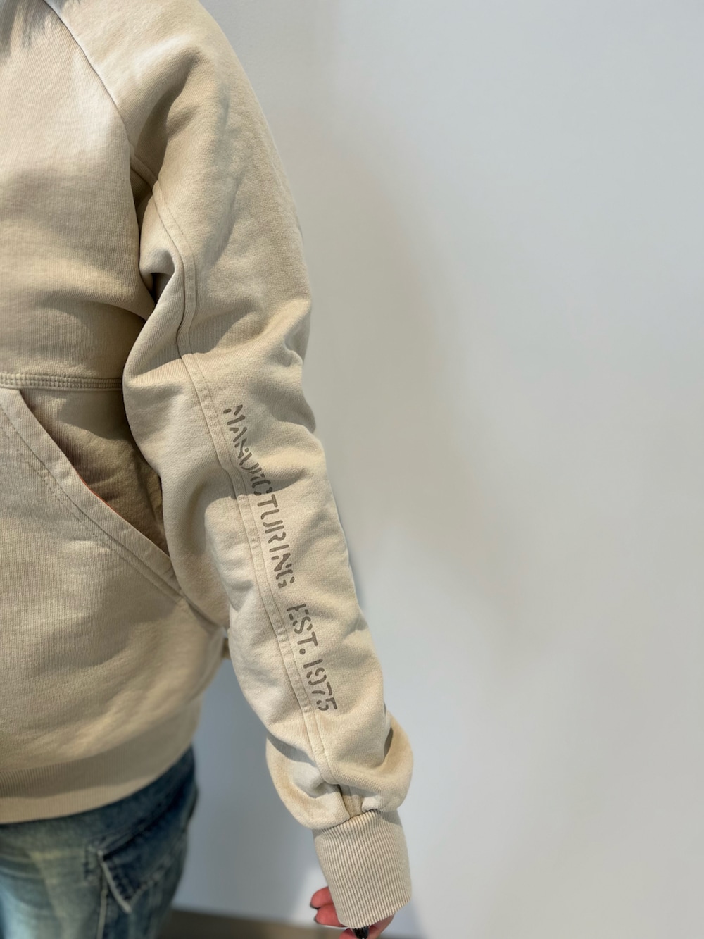 ベージュ系のスウェット、グリーン系のボストンバッグ、ブルー系のデニムパンツを着用したレディースの秋コーディネートの3枚目の写真