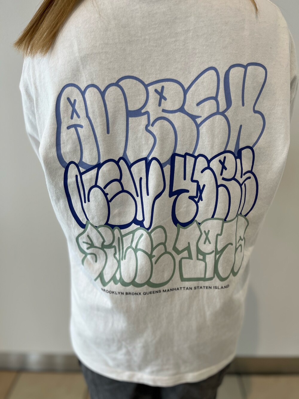 グリーン系のカーディガン/ボレロ、ホワイト系のTシャツ/カットソー、ブルー系のデニムパンツを着用したレディースの秋コーディネートの5枚目の写真